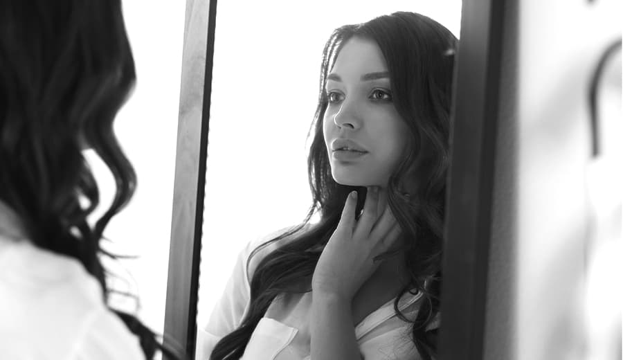 black and white photo of woman looking into mirror