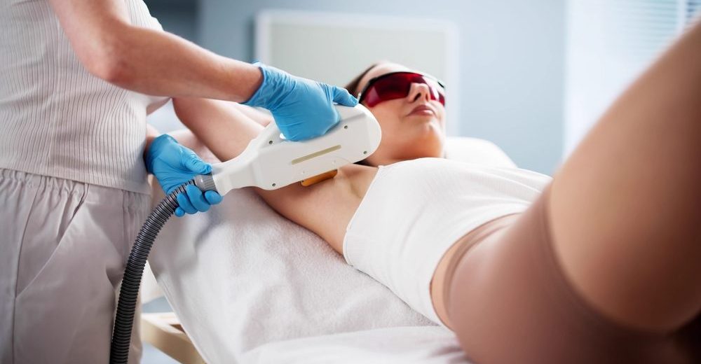 Woman receiving underarm laser hair removal treatment during a professional session